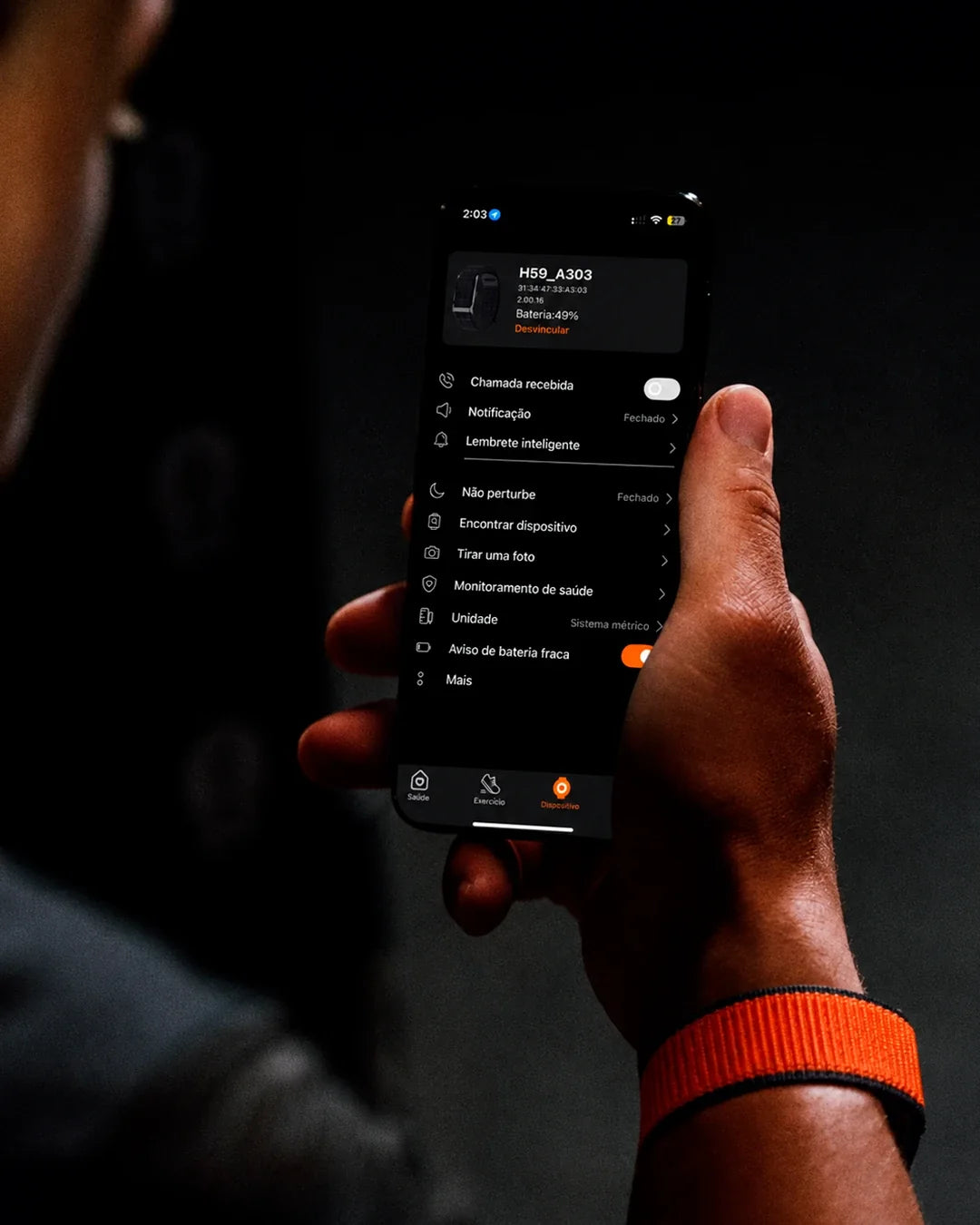 Pessoa com a pulseira QBand laranja consultando o app no celular