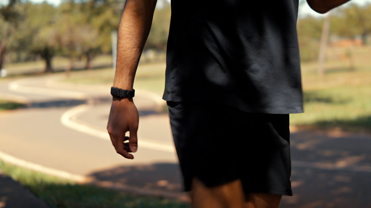 Pessoa caminhando ao ar livre com a pulseira QBand no pulso