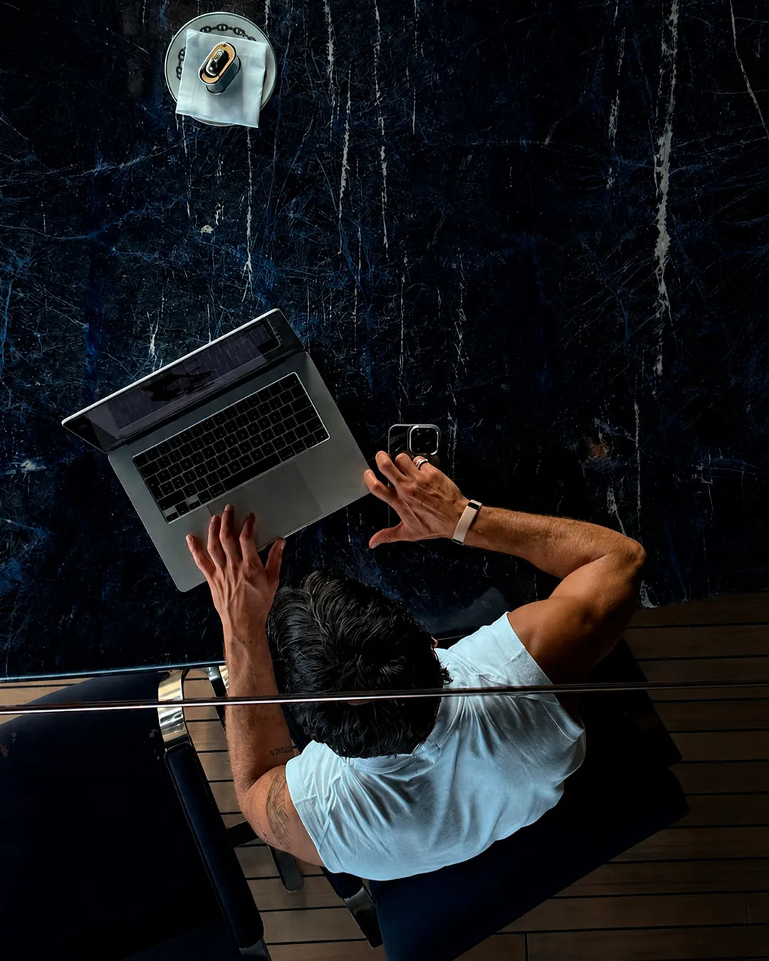 Pessoa trabalhando no notebook, vista de cima, com a pulseira QBand no pulso